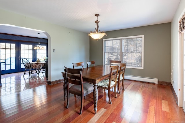 dining room with baseboards, wood finished floors, arched walkways, and a baseboard radiator