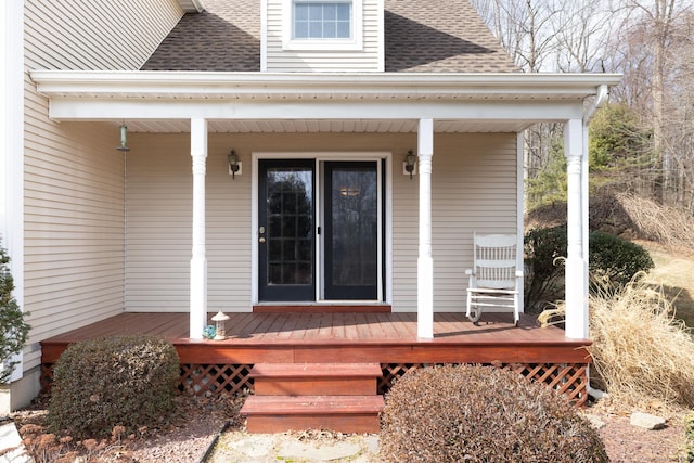 entrance to property featuring a shingled roof and covered porch