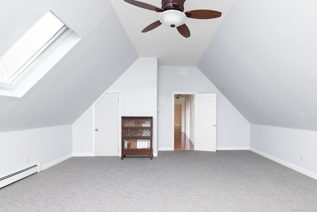 additional living space featuring a baseboard heating unit, vaulted ceiling with skylight, carpet flooring, and baseboards