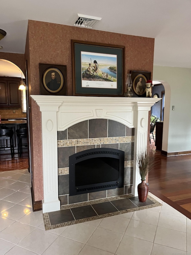 interior details with arched walkways, baseboards, visible vents, and a tiled fireplace