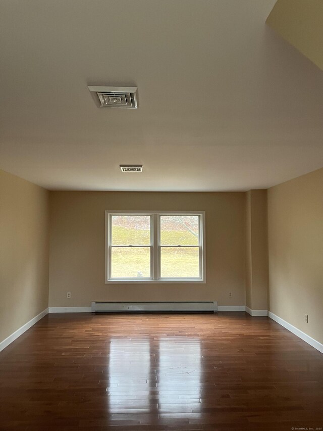 spare room with baseboards, visible vents, baseboard heating, and wood finished floors