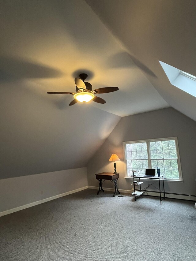 unfurnished room featuring lofted ceiling with skylight, a baseboard heating unit, carpet, and a ceiling fan