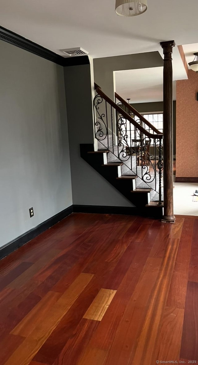 stairs with ornate columns, baseboards, visible vents, and wood finished floors