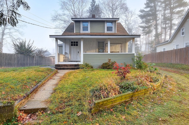 bungalow-style home featuring covered porch and a front lawn