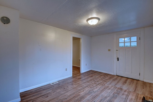 foyer with light hardwood / wood-style floors and a textured ceiling