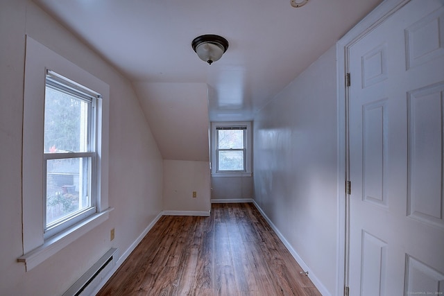 additional living space featuring light hardwood / wood-style floors, lofted ceiling, a baseboard radiator, and a wealth of natural light