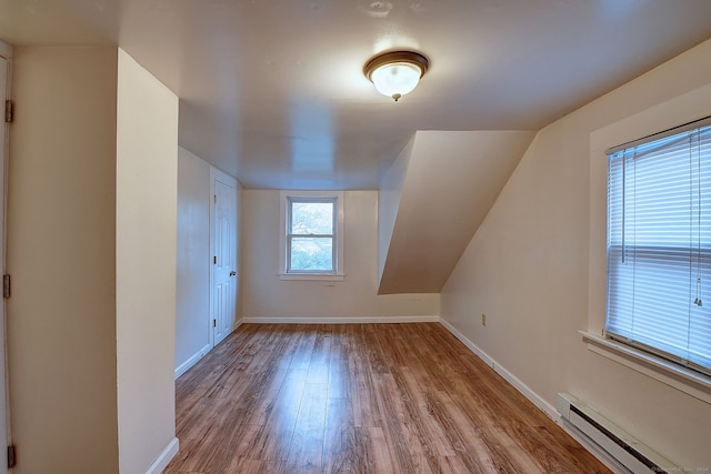 additional living space with light wood-type flooring and baseboard heating