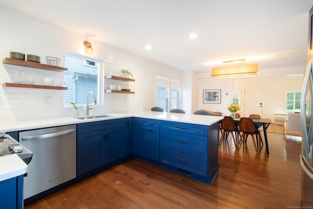 kitchen with sink, blue cabinets, dark hardwood / wood-style flooring, stainless steel dishwasher, and kitchen peninsula