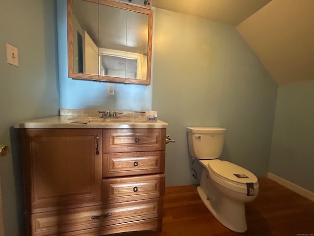 bathroom with toilet, hardwood / wood-style floors, vanity, and vaulted ceiling