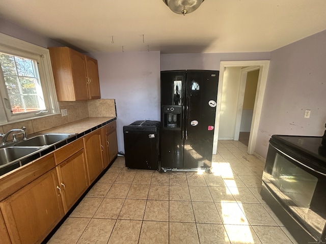 kitchen with black appliances, light tile patterned flooring, sink, tile counters, and decorative backsplash