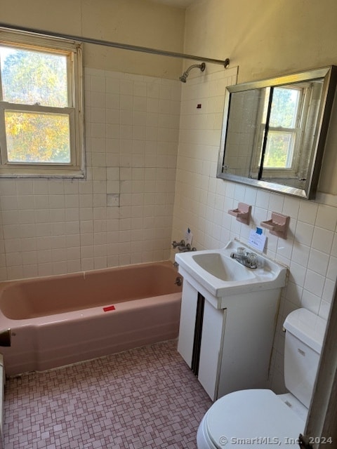 full bathroom with vanity, toilet, tile walls, and tiled shower / bath