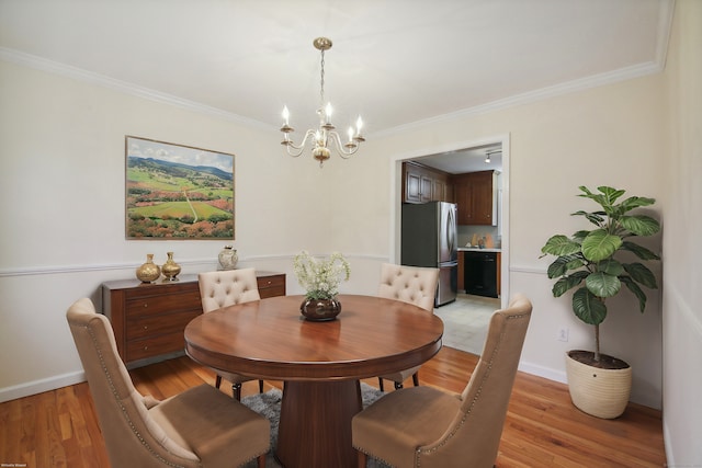 dining area featuring an inviting chandelier, ornamental molding, and light hardwood / wood-style floors