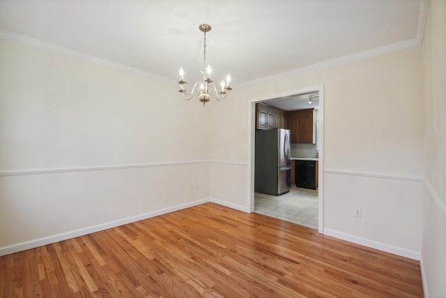 empty room with crown molding, a notable chandelier, and light wood-type flooring