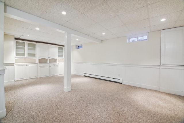 basement featuring a baseboard radiator, light carpet, and a drop ceiling