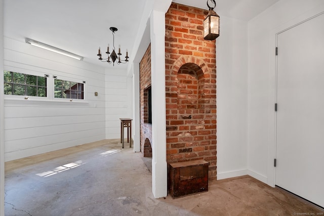 corridor featuring a notable chandelier and brick wall