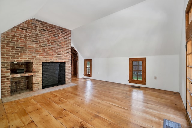 unfurnished living room with vaulted ceiling, light hardwood / wood-style flooring, and a fireplace