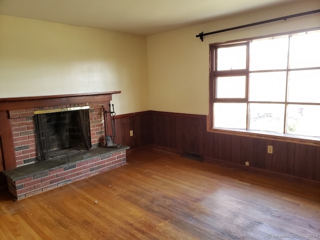 unfurnished living room with wood walls, wood-type flooring, and a fireplace