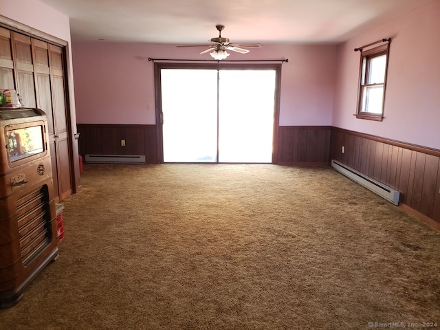 unfurnished bedroom featuring ceiling fan, a baseboard heating unit, and dark carpet