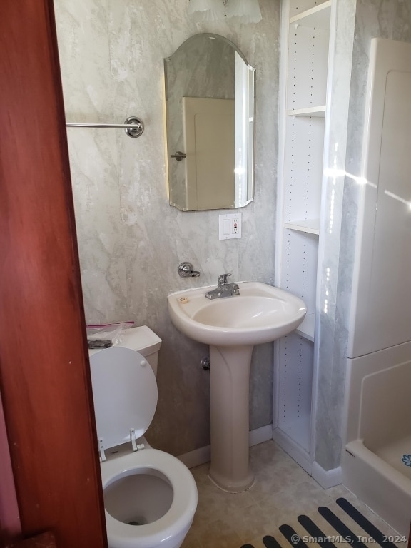 bathroom with toilet, walk in shower, and tile patterned floors