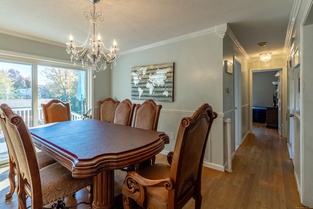 dining space with crown molding, a chandelier, a textured ceiling, and wood-type flooring