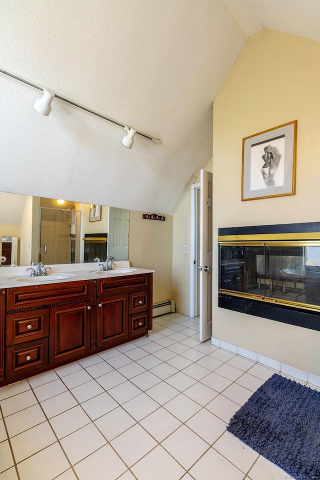 bathroom featuring a baseboard heating unit, tile patterned floors, a textured ceiling, vaulted ceiling, and vanity