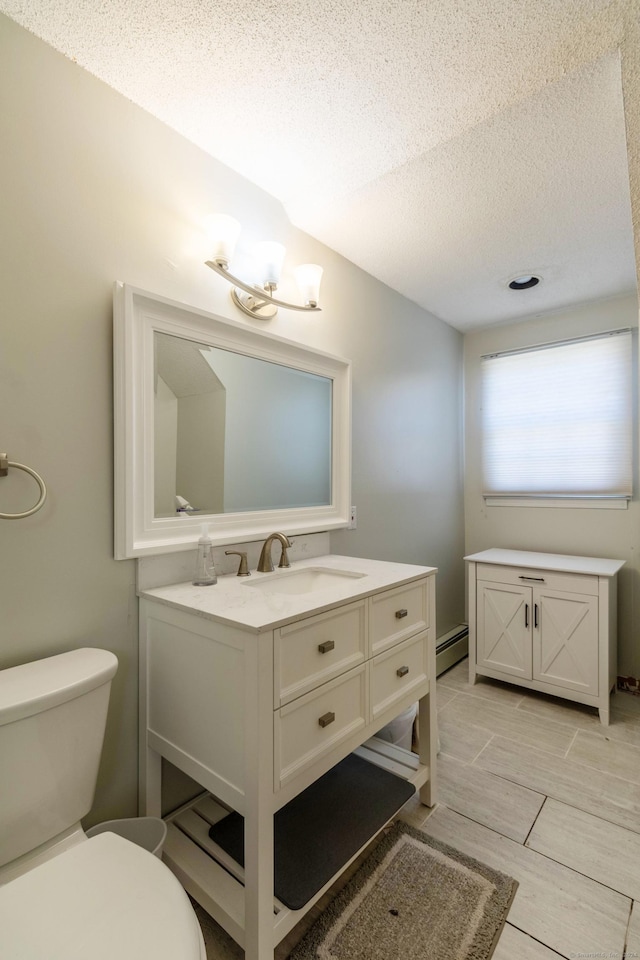 bathroom featuring vanity, toilet, a textured ceiling, and a baseboard radiator