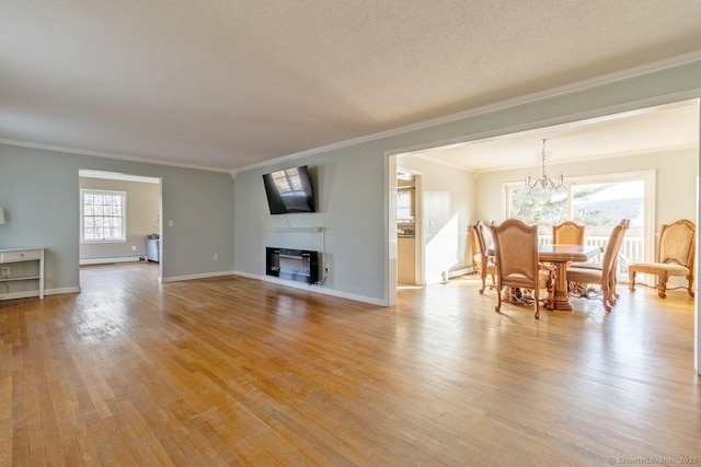 living room featuring crown molding, a fireplace, light hardwood / wood-style flooring, and a notable chandelier