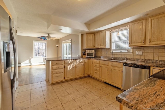 kitchen with kitchen peninsula, appliances with stainless steel finishes, light tile patterned floors, and sink