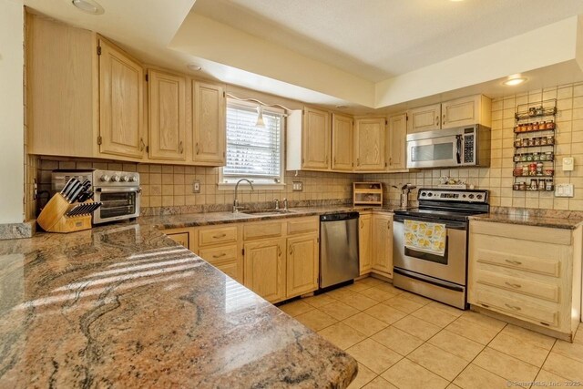 kitchen with light brown cabinets, sink, light tile patterned floors, and stainless steel appliances