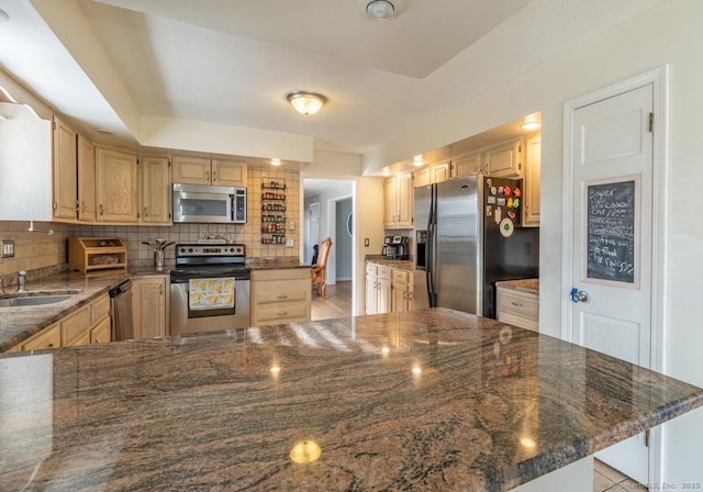 kitchen featuring light brown cabinetry, backsplash, stainless steel appliances, and dark stone counters