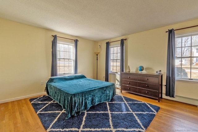 bedroom featuring multiple windows, hardwood / wood-style floors, and a textured ceiling