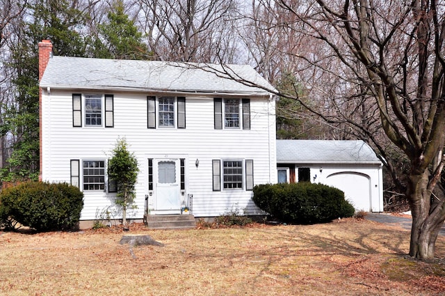 colonial house featuring a front lawn, a garage, and a chimney