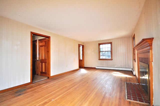 unfurnished living room with a baseboard heating unit, hardwood / wood-style flooring, a fireplace, and baseboards