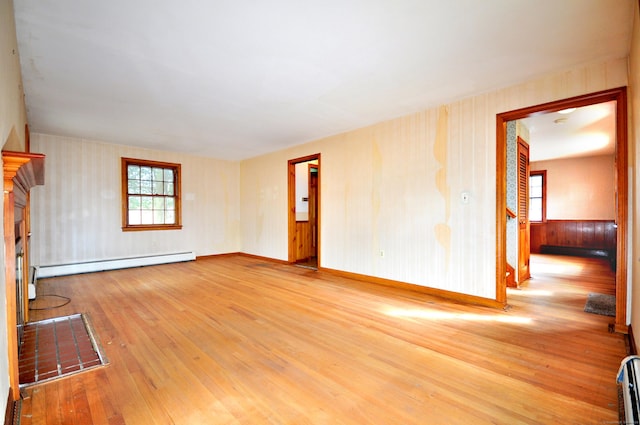 unfurnished room featuring hardwood / wood-style floors, baseboards, and a baseboard radiator