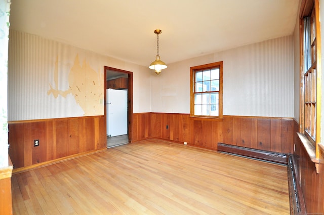 spare room featuring wood finished floors, a wainscoted wall, and baseboard heating