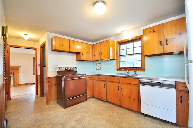 kitchen featuring white dishwasher, range with electric cooktop, a sink, light countertops, and brown cabinets