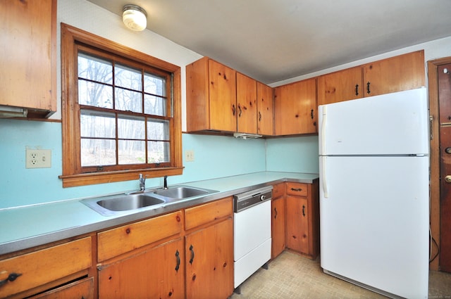 kitchen featuring a sink, white appliances, brown cabinets, and light countertops