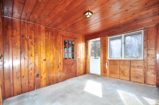 empty room with wooden walls, wood ceiling, and concrete flooring