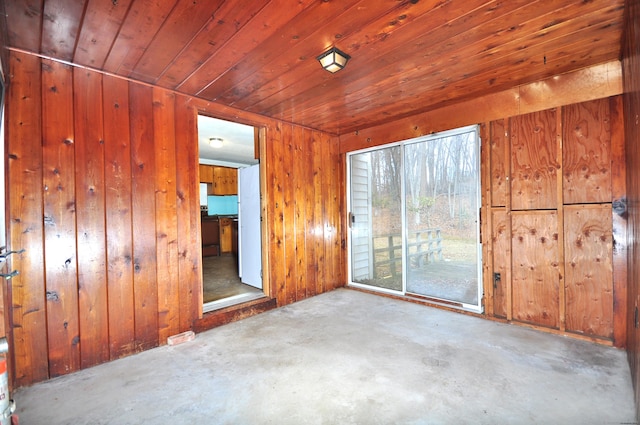 empty room featuring unfinished concrete floors, wooden walls, and wooden ceiling