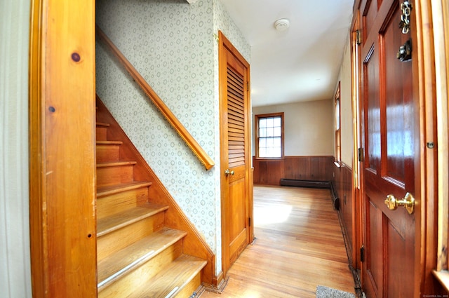 interior space featuring wallpapered walls, stairway, light wood-type flooring, wainscoting, and a baseboard radiator