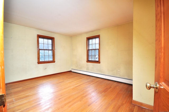 empty room with baseboards, baseboard heating, and wood finished floors