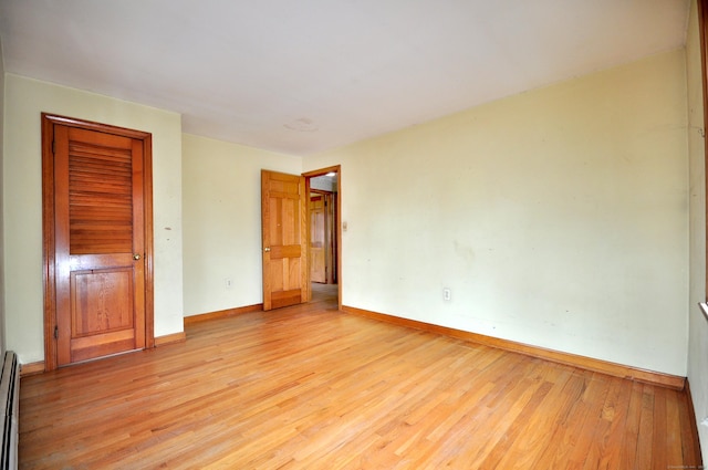 unfurnished bedroom featuring light wood-style floors, baseboards, and baseboard heating