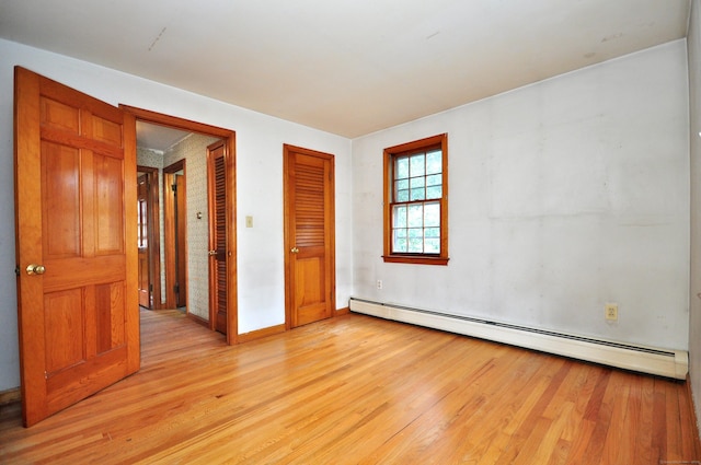 spare room featuring light wood finished floors and baseboard heating