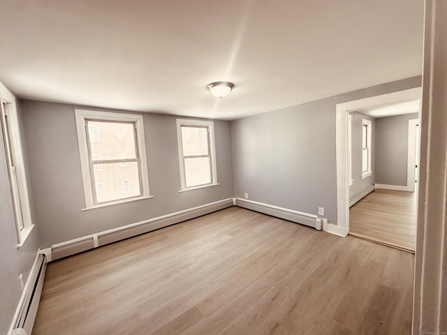 empty room with light wood finished floors, a baseboard radiator, a baseboard heating unit, and baseboards