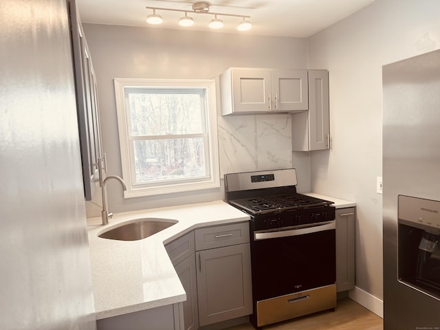 kitchen featuring stainless steel appliances, gray cabinets, light countertops, and a sink