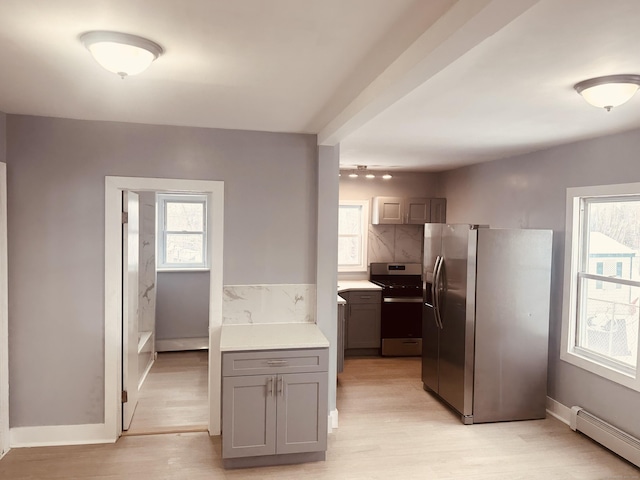 kitchen with a baseboard heating unit, stainless steel appliances, light countertops, gray cabinets, and light wood finished floors