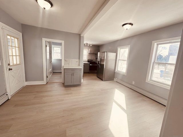 interior space with a baseboard radiator, stainless steel appliances, light countertops, baseboard heating, and light wood-type flooring