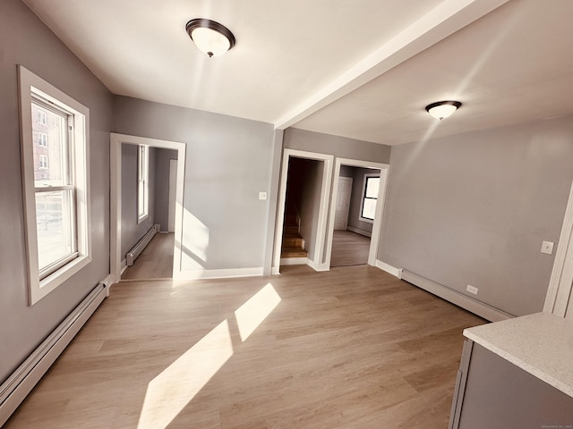 unfurnished room with a baseboard radiator and light wood-style floors