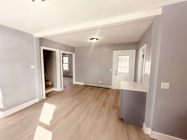 unfurnished dining area with stairs, a baseboard radiator, light wood-style flooring, and baseboards