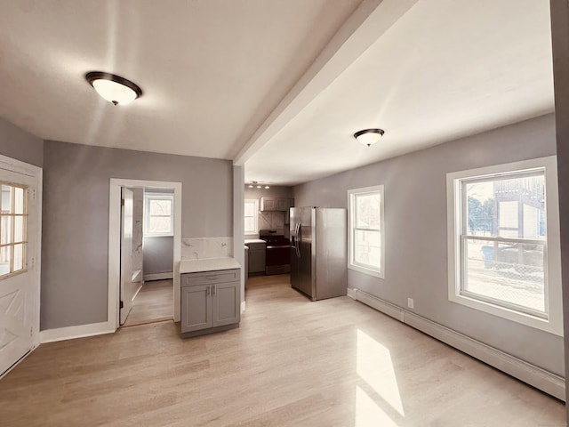 interior space with baseboards, plenty of natural light, light wood-style flooring, and baseboard heating